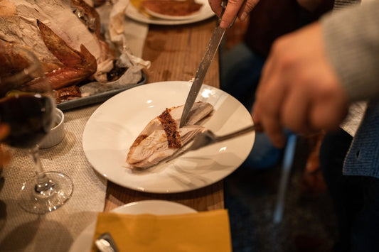 Slicing roast turkey breast onto a plate at a Thanksgiving table.