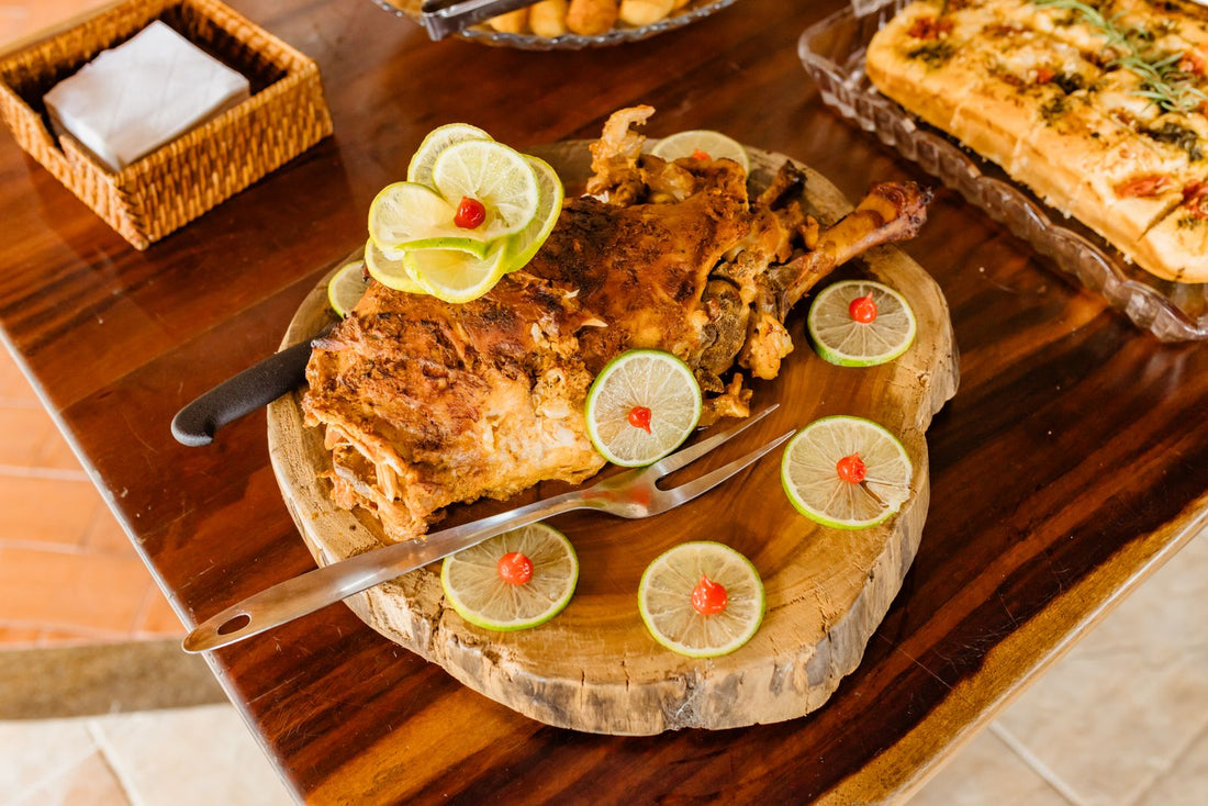 A roasted bird with lime slices on a wooden serving board.