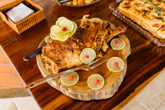 A roasted bird with lime slices on a wooden serving board.