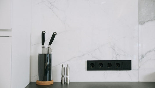 Kitchen knives stored upright in a round knife holder on a white marble countertop.