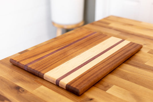 A striped maple and walnut cutting board on a butcher block counter.