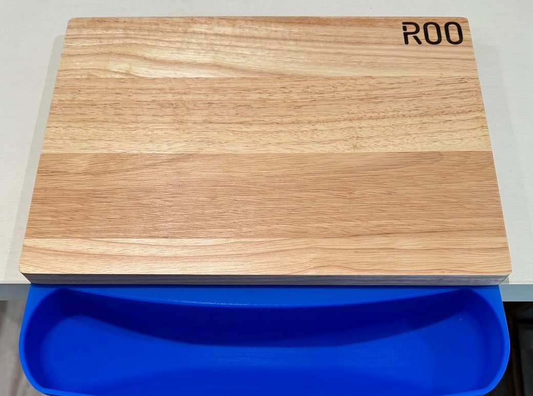 The ROO silicone mat under a rubberwood cutting board, its scrap pouch hanging over the counter edge