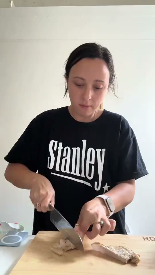 Home cook dicing chicken on the ROO rubberwood cutting board for a meal prep salad